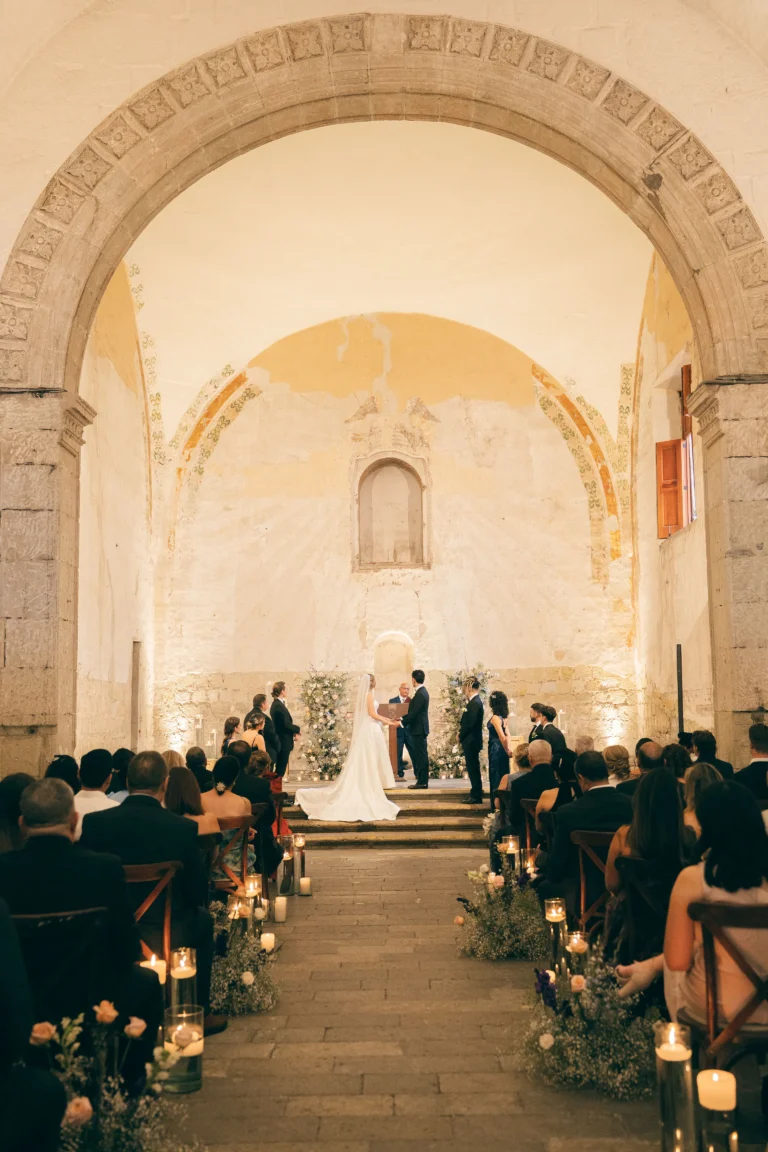 Boda multicultural: Fotografía de lejos de una pareja de novios de pie en el altar de una iglesia en su boda.