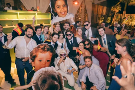 Boda en Oaxaca: Fotografía de un grupo de personas durante la recepción de una boda sosteniendo banderas de España.